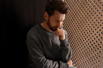 Upset man listening to priest during confession in booth