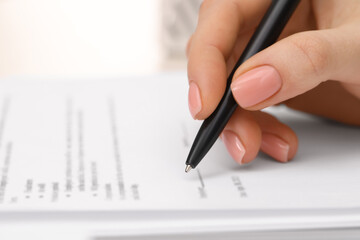 Woman signing document with pen, closeup view