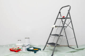 Fototapeta na wymiar Metallic folding ladder and painting tools indoors, space for text