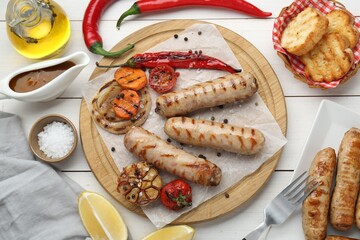 Tasty grilled sausages served on white wooden table, flat lay