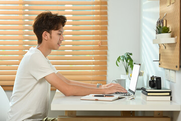 Man in casual clothes using laptop computer at home. Freelance, creative occupation, e-learning concept