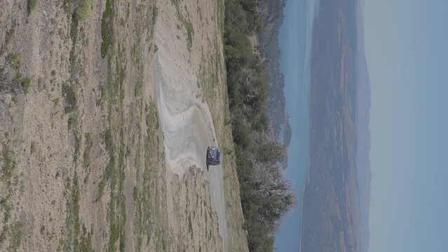 A car dring along a road in the hills of Patagonia, Argentina with mountains and a lake in the background