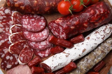Different types of delicious sausages and tomatoes on wooden board, flat lay