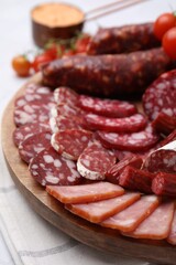 Different types of delicious sausages, sauce and tomatoes served on white table, closeup