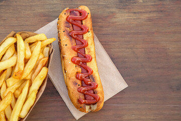 Fresh tasty hot dog and french fries on wooden table, flat lay. Space for text