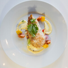 Healthy chicken with breadcrumbs, side salad & white sauce on a white plate.