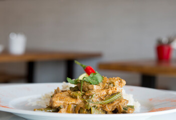 Healthy chilli curried chicken on a white plate in a restaurant, 