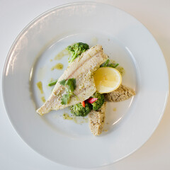 Healthy fish dish with cuscus & broccoli on a white plate.