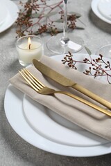Stylish table setting with cutlery, burning candle and eucalyptus leaves