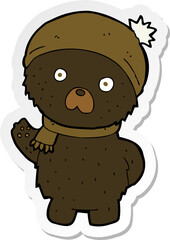 Fototapeta premium sticker of a cartoon cute black bear in winter hat and scarf