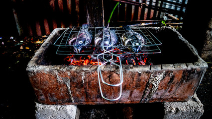 Tilapia fish being grilled on a traditional grill