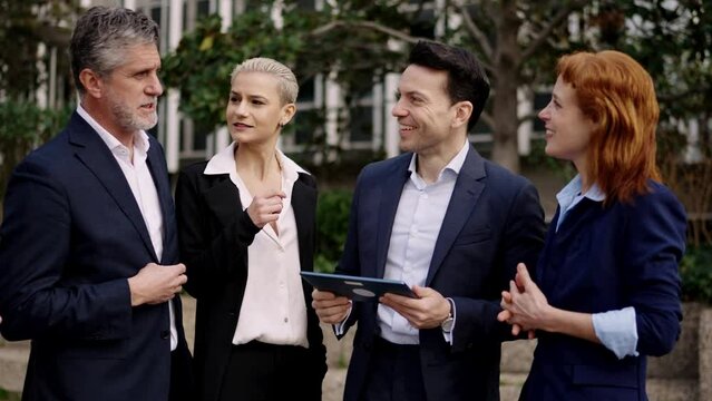 Discussion between business people using a tablet standing outdoors