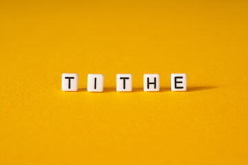 Tithe - word concept on building blocks, letters