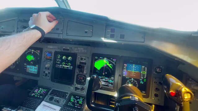 First person view of a pilot adjusting the buttons in the cockpit of an airplane