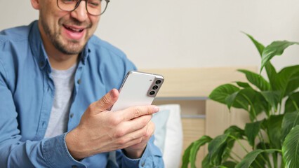 Man using smartphone pressing finger, reading social media internet, typing text or shopping online. Mobile phone in two hands at home