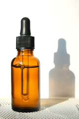 The amber glass dropper bottle with the serum inside casts a shadow. Vertical image, flat lay, copy space.