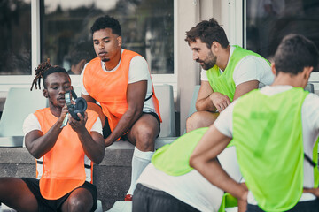 Men, relax or rugby team with headphones on break, exercise workout or training for a game. Music, friends relaxing or sports people bonding, talking or resting after practice match on bench together