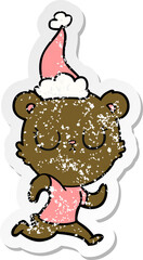 peaceful distressed sticker cartoon of a bear running wearing santa hat