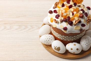 Traditional Easter cake with dried fruits and decorated eggs on white wooden table, closeup. Space for text