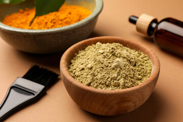 Bottle, henna and turmeric powder on coral background, closeup. Natural hair coloring