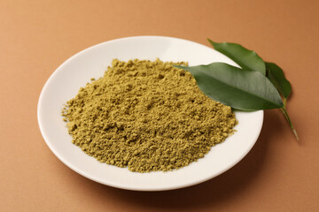 Henna powder and green leaves on coral background. Natural hair coloring