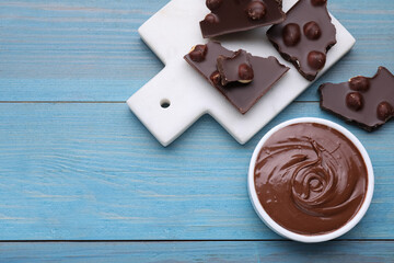 Tasty homemade paste and pieces of chocolate on light blue wooden table, flat lay. Space for text
