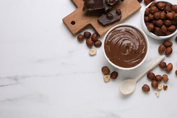 Bowl with tasty paste, chocolate pieces and nuts on white marble table, flat lay. Space for text