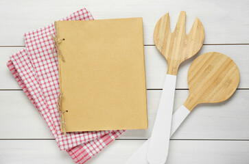 Blank recipe book and kitchen utensils on white wooden table, flat lay. Space for text