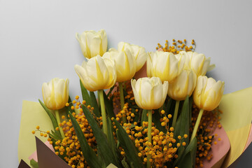 Obraz premium Bouquet with beautiful tulips and mimosa flowers on light grey background, top view