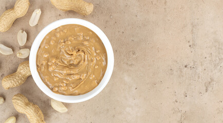 Crispy peanut butter in a bowl and peanuts on a beige background. Top view. Copy space. American...