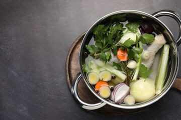 Different ingredients for cooking tasty bouillon in pot on black table, top view. Space for text