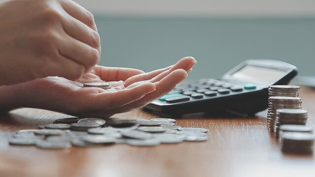 Businessman hand pressing calculator putting coins on pile saving savings for retirement future The idea of ​​saving money for the future and life.