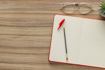 Ballpoint pen, notebook and glasses on wooden table, flat lay. Space for text