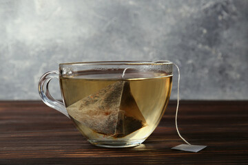 Tea bag in glass cup on wooden table, closeup