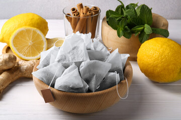 Tea bags, mint, lemons and ginger on white wooden table, closeup