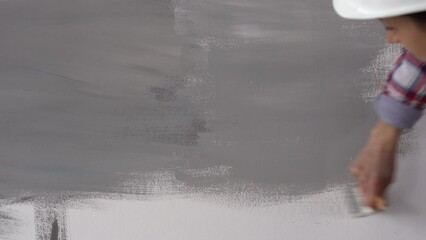 Brush Painting, Female worker painting on surface wall painting apartment, renovating with gray color paint.