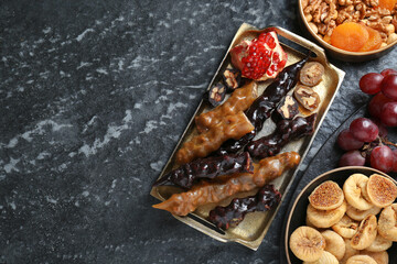 Delicious sweet churchkhelas and ingredients on textured table, flat lay. Space for text