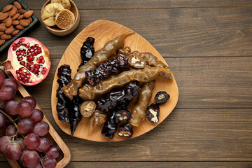 Delicious sweet churchkhelas and ingredients on wooden table, flat lay. Space for text