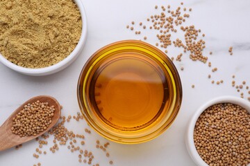 Bowl of natural oil, mustard seeds and powder on white marble table, flat lay