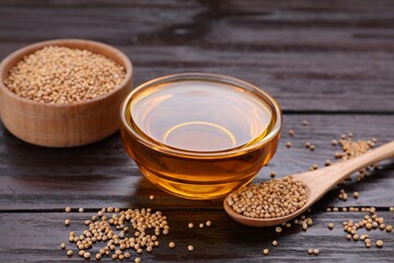 Bowl of natural oil and mustard seeds on wooden table