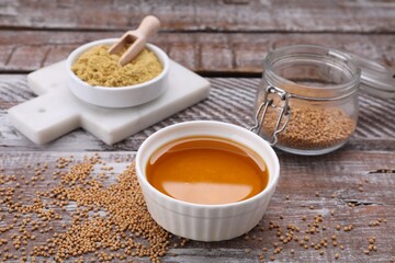 Bowl of natural oil, mustard seeds and powder on wooden table