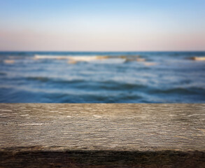 Naklejka na ściany i meble Natural, abstract, unfocused background. Seascape. An empty wooden base, a wooden table, a tabletop against the background of sunset, dawn on the seashore. Copy space