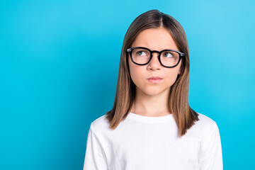 Fototapeta premium Photo of thoughtful schoolgirl with straight hairdo dressed white shirt look at offer empty space isolated on blue color background