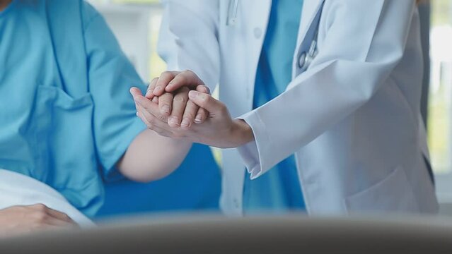 Doctor giving hope. Close up shot of young female physician leaning forward to smiling elderly lady patient holding her hand in palms. Woman caretaker in white coat supporting encouraging old person