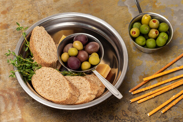 Dark olives and baguette pieces in a metal bowl. Green olives in a bowl.