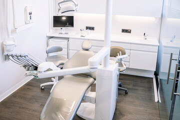 Leather dental chair with various medical instruments located in white dentist office