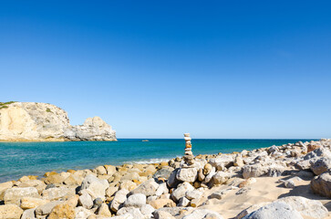 Beautiful seascape with stone pyramid (cairn) on the Praia do Barranco Beach. Sagres (Vila do...
