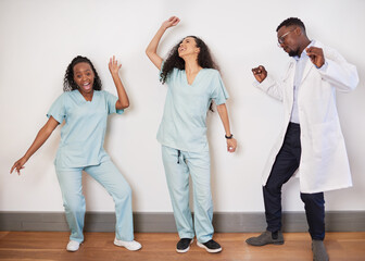 Team of three medical professionals dance on a break, doctor having fun