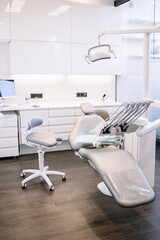 Interior of contemporary tidy dental clinic with white chair and white furniture equipped with modern dental machine and instruments