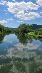River Uzh near the village of Perechyn, reflection of clouds in the water, spring sunny day in the Carpathians of the Transcarpathian region of Ukraine